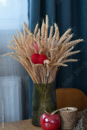 Still life with rustic wheat bouquet with red heart in vase on wooden table. Selective focus. Low DOF