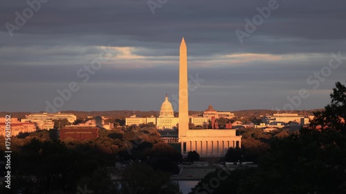 Golden sunset light bathes the Washington Monument, Lincoln Memorial, and U.S. Capitol on an autumn evening in Washington, D.C., with dramatic clouds over the National Mall.