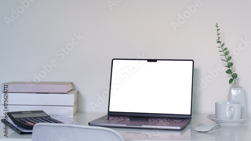 Modern home office with blank screen laptop and simple decorative items.