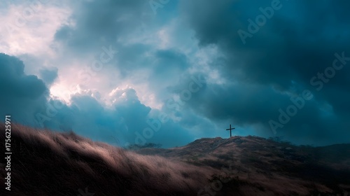 A solitary cross stands atop a windswept hill under a dramatic brooding sky with light breaking through the clouds