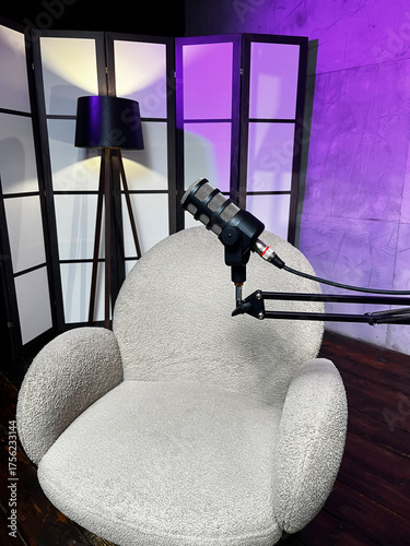 Podcast setup with microphones and a cozy chair in a modern studio space