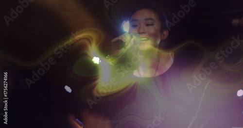 Singing Chinese singer in black long sleeve top on concert stage, with microphone, haze and lights