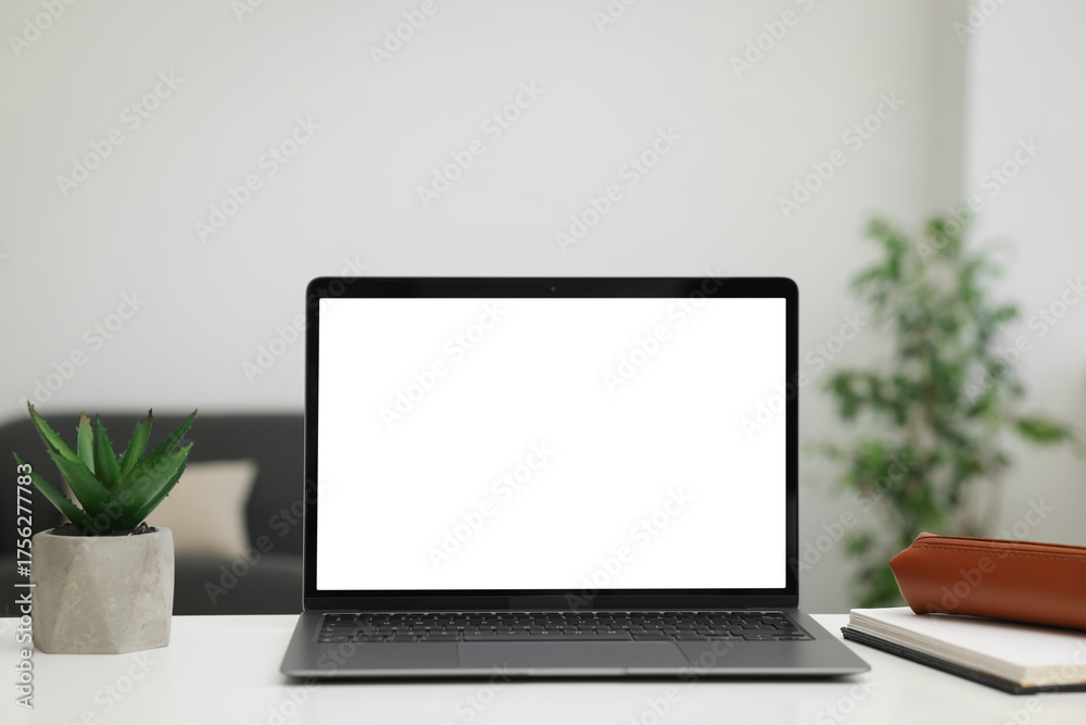 Fototapeta premium Laptop, notebook and plant on white desk indoors. Mockup for design
