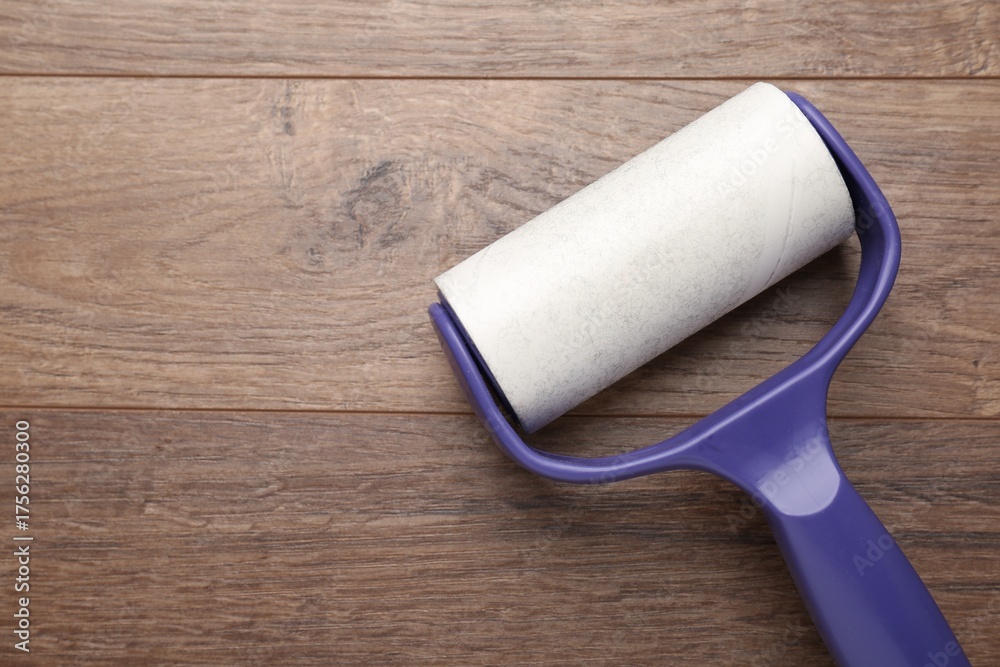 Obraz premium Sticky lint roller on wooden table, top view. Space for text