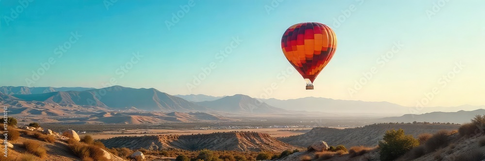 Fototapeta premium A vibrant hot air balloon, soaring gracefully through a clear blue sky, casting a long shadow on the landscape below Perfect for travel, adventure, and freedom concepts , elevation, beautiful