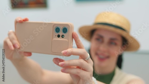 Museum aesthetics through the eyes of a young female visitor taking selphie photos of modern paintings. Cultural experience and digital interaction.
