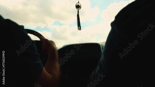 Close-up of a man's hand gripping the steering wheel while driving through dry savanna, with blurred sky scenery rushing past the window, evoking freedom, adventure, and solitude. Hand hold shot.