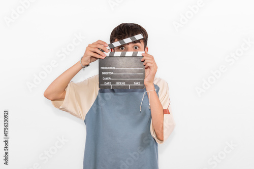 young casual dressed Generation Z influencer white male model teenage boy prepares to create and direct social media film reel with blank clapperboard slate. plain background studio setting