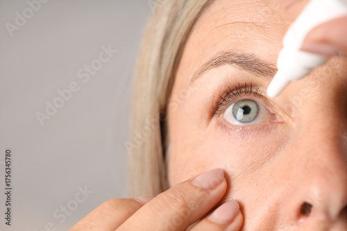 Fotografía Woman applying eye drops on light background, closeup