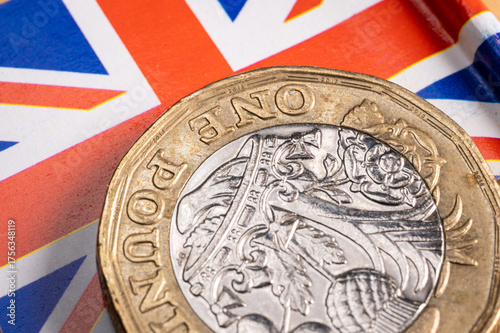 United Kingdom pound coin resting on a British flag, symbolizing the nation's economic challenges, debt, and the financial mild stagflation scenario