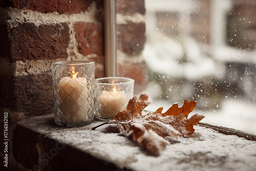 Wallpaper Mural Cozy winter scene with lit candles and frosted oak leaves on a windowsill as snow falls gently outside Torontodigital.ca