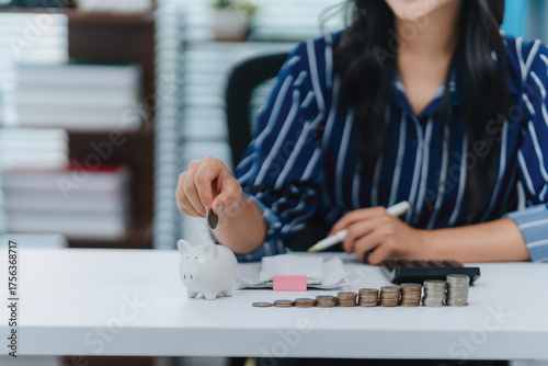 Saving for the Future: An individual meticulously places a coin into a piggy bank, symbolizing careful financial planning, stability, and prudent saving for the future.