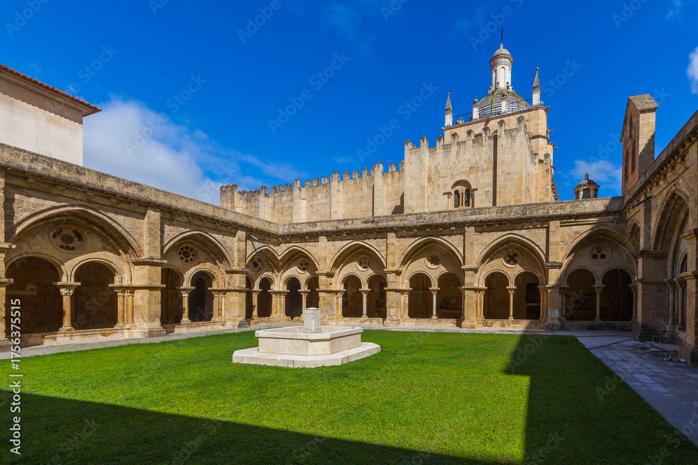 Fototapeta premium A sunlit courtyard with a central stone fountain is surrounded by arched cloisters
