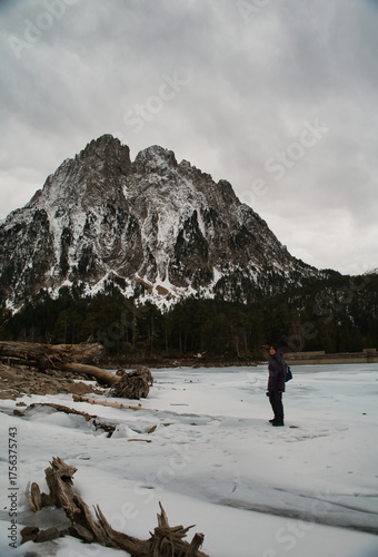 Girl hiking while observing Los Encantados, or Els Encantats in Catalan. These are two peaks that rise above the frozen lake of Sant Maurici. In Agüestortes National Park, Spain.