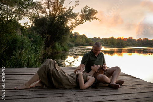 Romantic Couple Enjoying a Serene Sunset by the Lake on a Wooden Dock