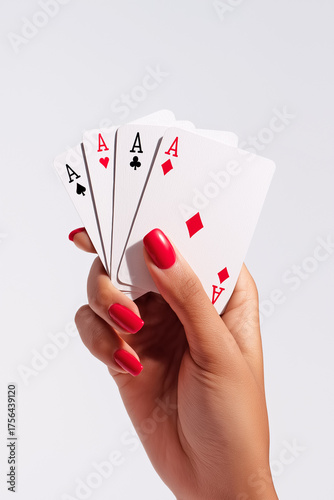 Female hand with red nail polish holding four aces from a standard deck of playing cards isolated on bright neutral background. Copy space, aspect ratio 9:16
