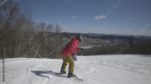 4K video of a woman snowboarding slow motion down a cold winter mountain on a sunny snowy day at Killington, Vermont, New England, USA. Thrill and excitement. 