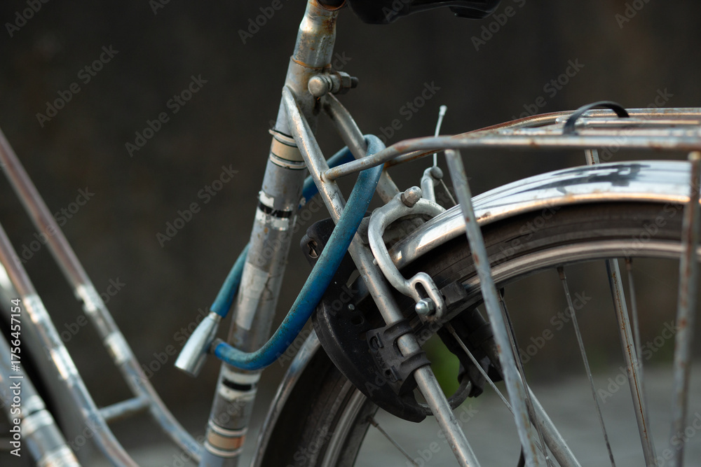 Obraz premium Close-up of a classic city bicycle with a blue lock on the rear wheel. Urban lifestyle and transportation concept.