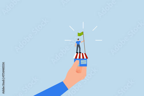 Small business idea, successful entrepreneur waving a victory flag in a small shop held by a gigantic hand