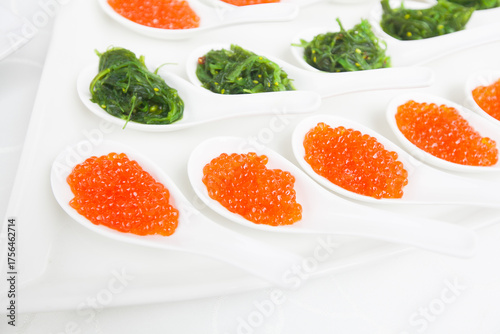 red caviar close-up in white spoons on banquet