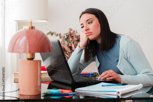A young female student appears frustrated while typing on her laptop, clearly struggling with her assignments and feeling overwhelmed by academic pressures. She embodies stress and concentration.
