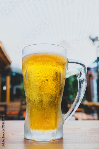 50 cl pint of beer served on wooden surface. Cold beer glass on wooden table. Refreshing golden beer in glass on wooden table. Full glass of lager beer on wooden table.