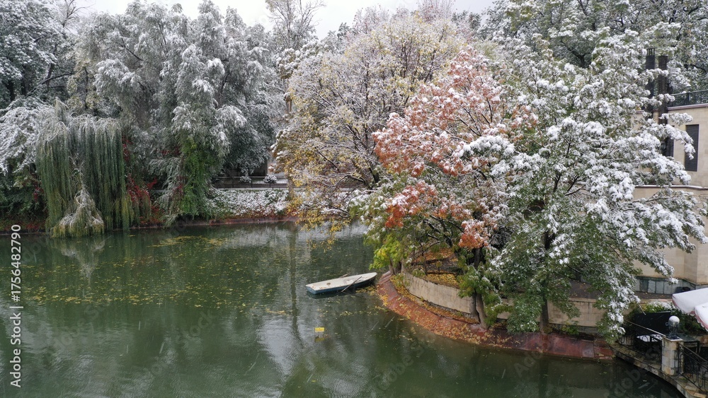 Fototapeta premium First snow falling on autumn trees lining river