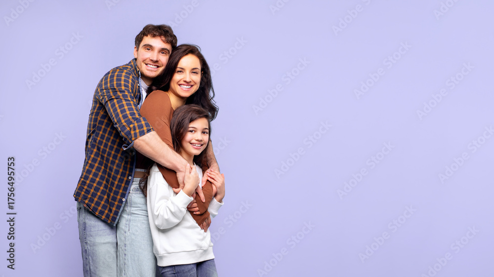Fototapeta premium Family portrait. Happy loving father, mother and their daughter posing isolated on purple studio background, hugging each other and smiling at camera, panorama with free space