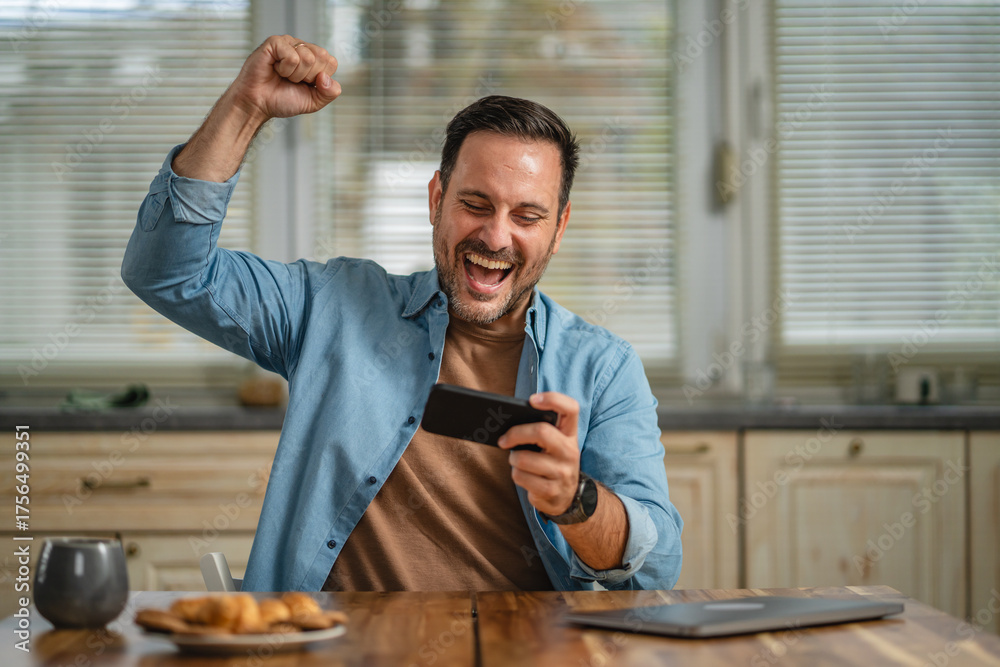 Fototapeta premium Man winning online game on smart phone celebrating success
