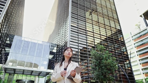 Businesswoman walking in modern city with tablet in slow motion
