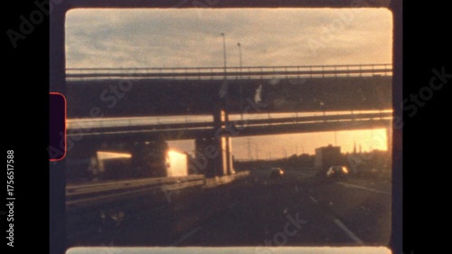 Sunset light glows through highway overpass during a nostalgic drive captured on vintage 8mm film with authentic analog film grain and soft focus