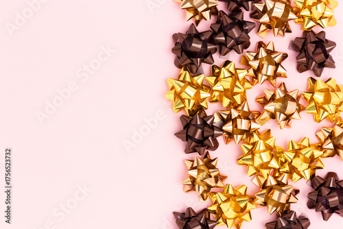 Bows made from golden ribbons on a pink background with copy space.