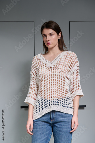 A girl model in stylish clothes poses on a gray background.