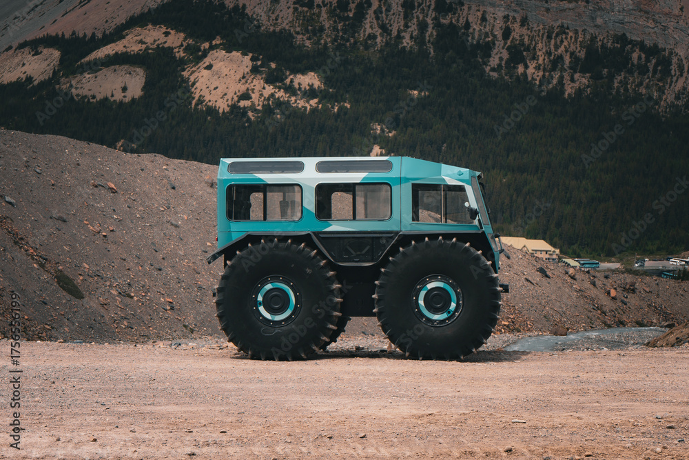 Obraz premium Off-road vehicle with oversized tires parked in mountain landscape.