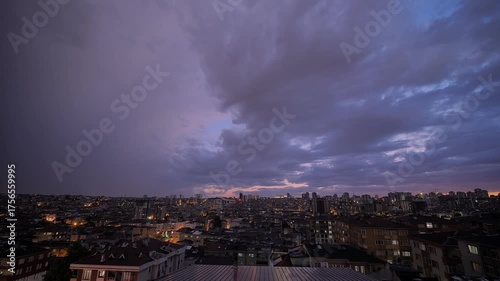 Time lapse: fast moving thunderstorm clouds in the dark sky over typical turkish residential buildings with warm illumination and blinking windows in Istanbul, Turkey at night: time lapse, wide angle