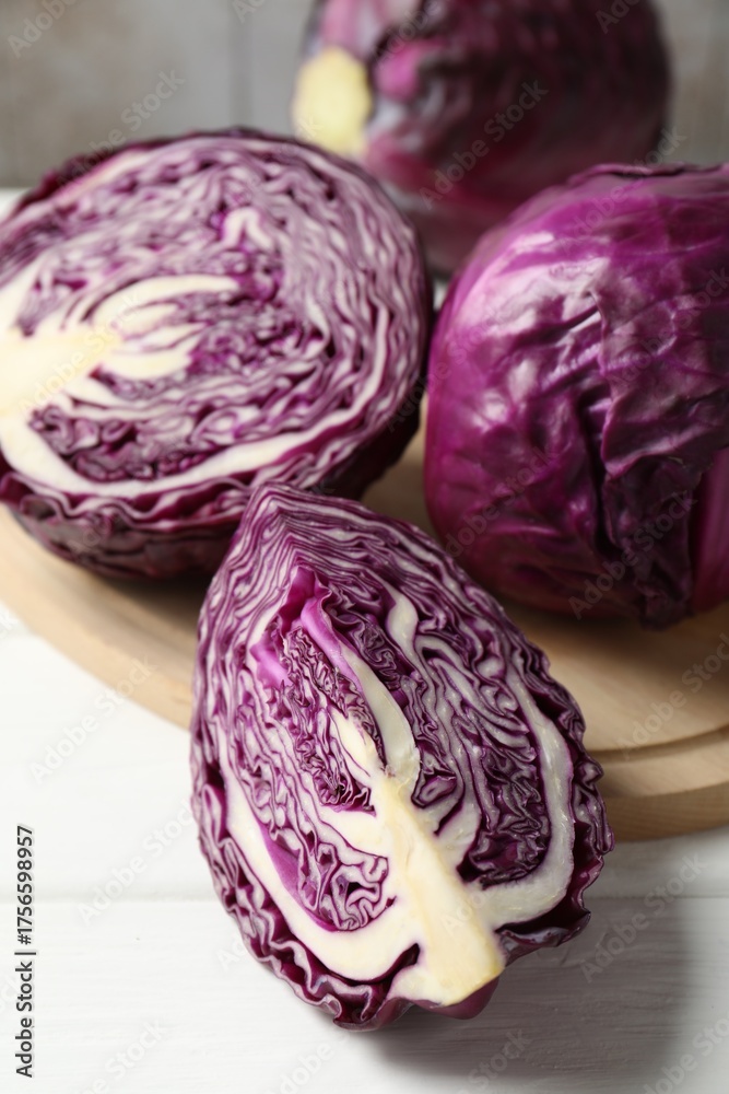 Obraz premium Whole and cut fresh red cabbages on white wooden table, closeup