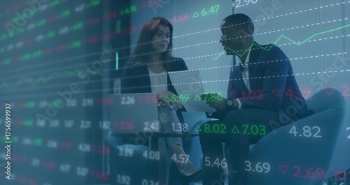 Discussing mid adult colleagues reviewing market charts in corporate lounge, with laptop and tablet