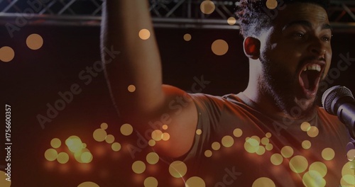 Adult singer raising arm, singing on stage under truss with microphone and bokeh lights, copy space