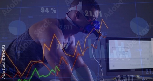 Pedaling male wearing gas analysis mask on stationary bike in science lab, with computer charts