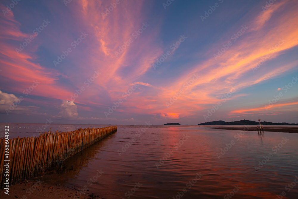Obraz premium The tranquil lake reflects the fiery hues of sunset, where orange, pink, and violet merge into calm waters. Gentle ripples shimmer beneath a peaceful sky capturing the serene beauty of nature.