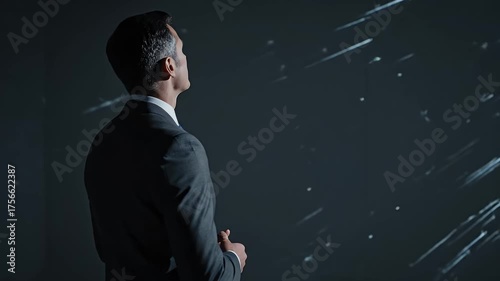 Pensive Businessman in Dark Suit Standing Contemplating Stars Projected on Screen With Dramatic Lighting And Minimal Background