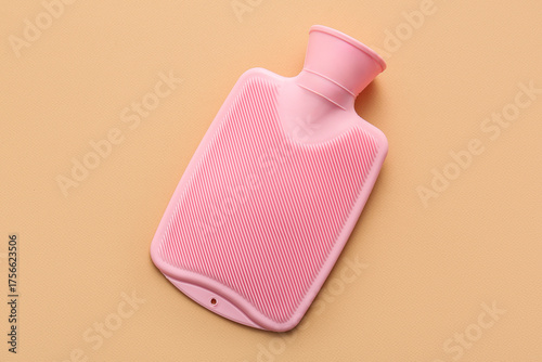 Foto Pink hot water bottle on beige background