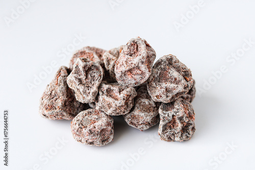Closeup of a pile of salted preserved plums (kiamboy asin asem) coated with a powdery white layer, isolated on a white background.