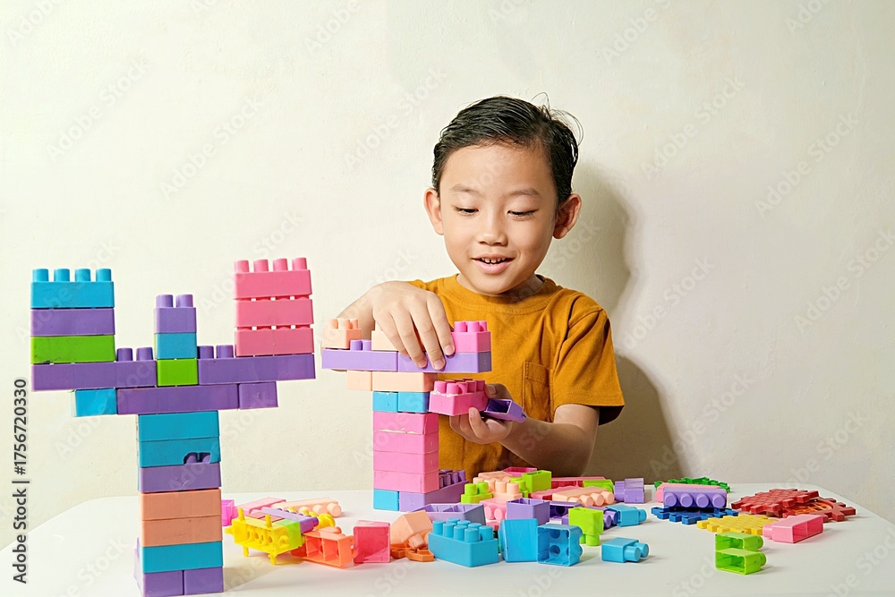Fototapeta premium A focused young boy assembling colorful plastic blocks during creative playtime. 