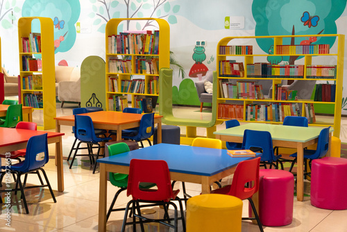 Photograph of a children's student area with books, tables, and chairs without people in a colorful and friendly environment.