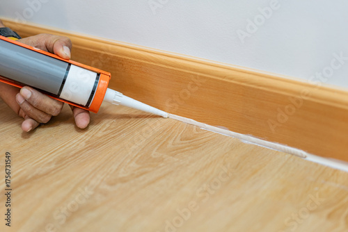 Hand Applying Caulk Sealant to Baseboard Gap