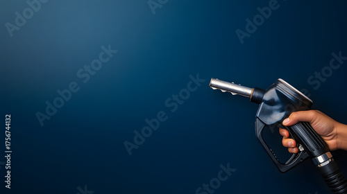 Hand holding a petrol pump nozzle on a blue background with space for text. Illustration of a banner background for the oil and fuel industry concept.