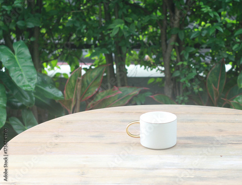 White coffee cup on a wooden table in a refreshing garden