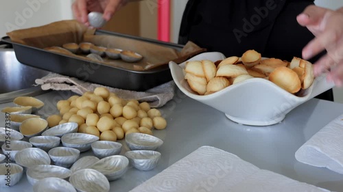 Crafting baked shells on countertop, Bakery scene with warm tones and baking tools visible, Preparing baked shells beside dough balls with tools and napkins on counter