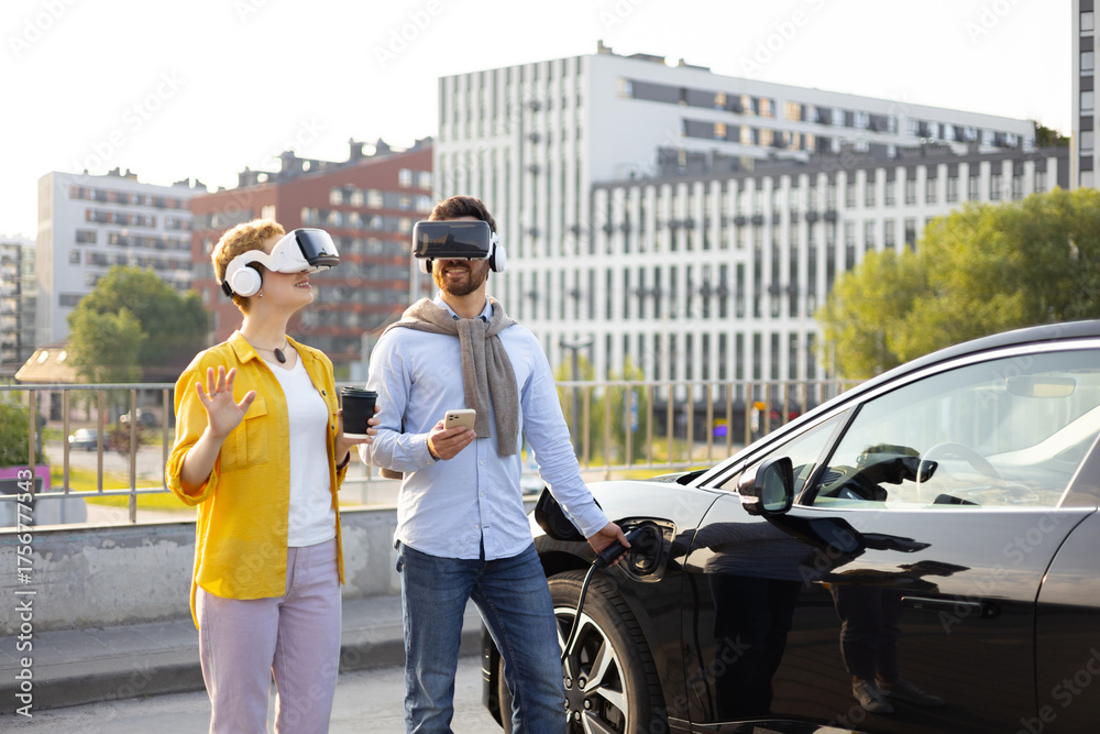 Fototapeta premium A couple wearing VR headsets while charging an electric vehicle in an urban setting.